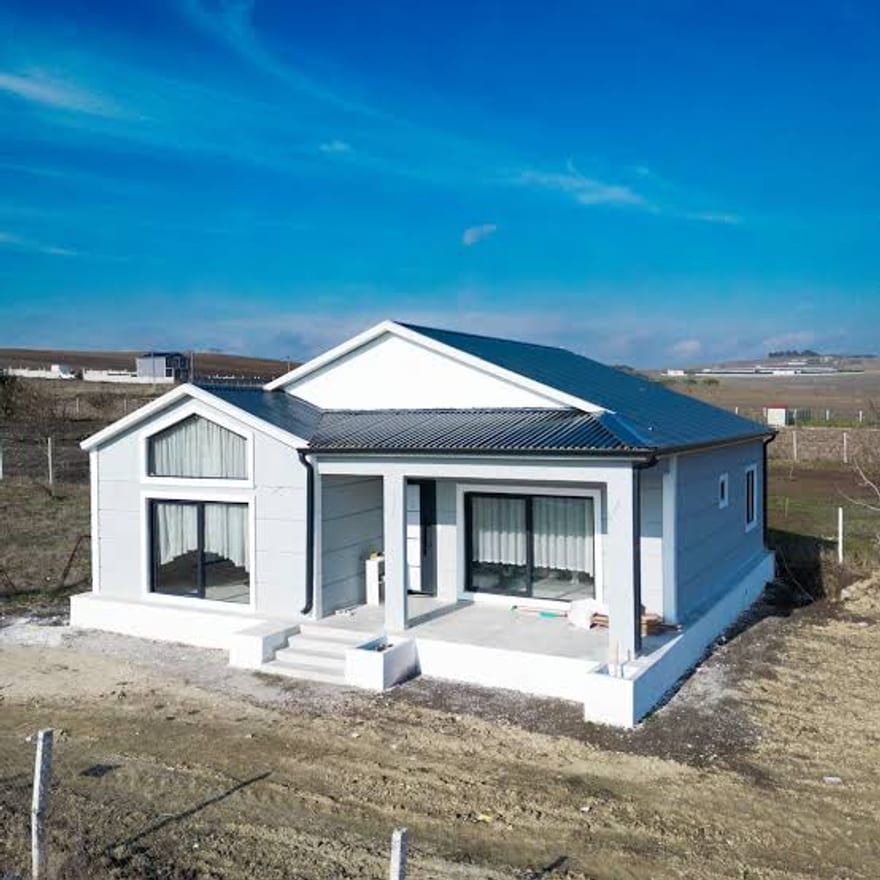 Mavi çatılı, beyaz cepheli, girişi merdivenli prefabrik konut